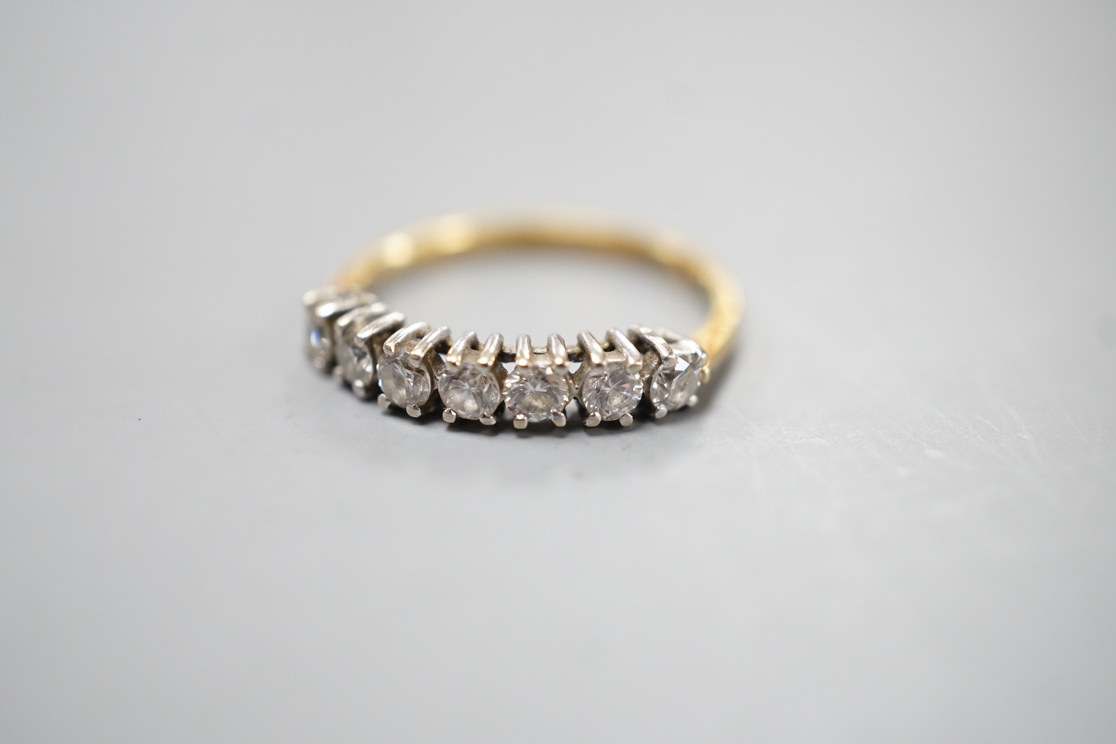 An 18ct gold and seven stone diamond set half hoop ring, size K, gross weight 1.8 grams.